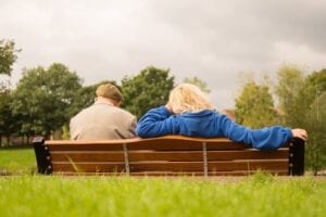 Elderly man and care worker sitting outdoors in a nature park